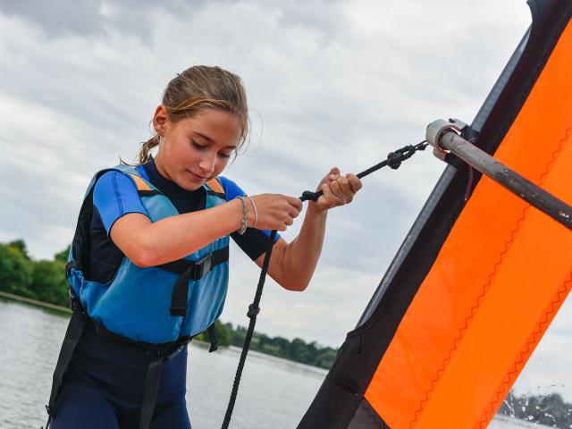 Une jeune fille apprend à faire de la planche à voile