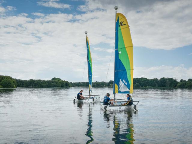 Deux catamarans naviguent sur le plan d'eau de La Rincerie