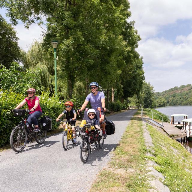 Une famille à vélo longe la rivière la Mayenne sur le chemin de halage